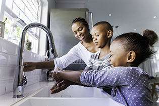 Mother helping children wash their hands.