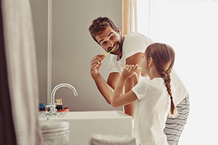 Father brushing teeth with daughter.